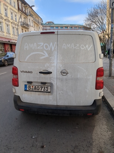 a dirty white van. someone cleaned it in the shape of an amazon logo